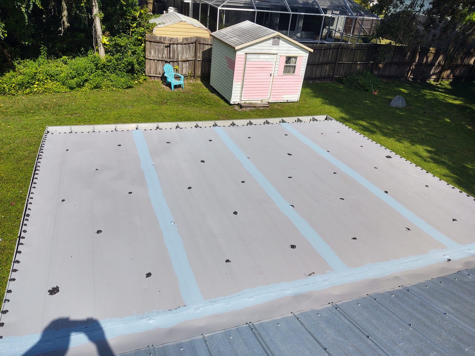 The same corrugated metal roof after coating, with reinforced seam stripes visible across the panels
