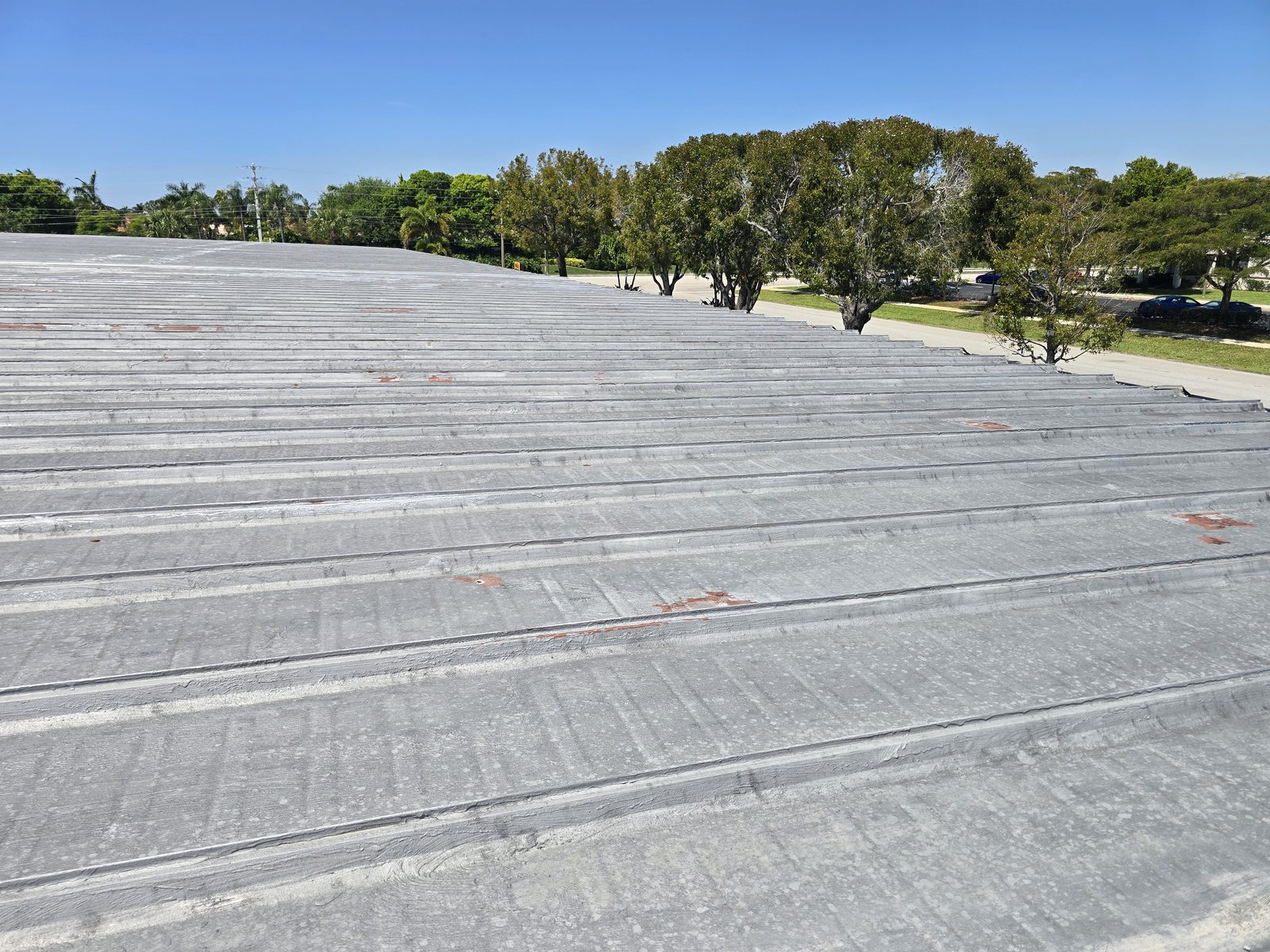 Long run of weathered metal roofing viewed along the panels during a roof survey
