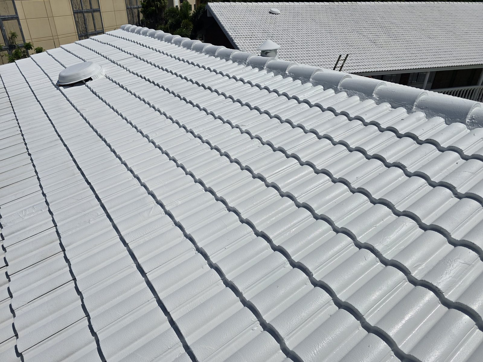 Concrete barrel tile roof after a full white reflective coating, ridge and field evenly covered